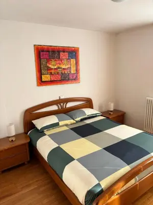 a bedroom with a bed with a blue and white checkered blanket at Appartamento Dolomiti in Castello di Fiemme