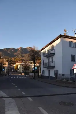 an empty city street with a white building and mountains at La casa dela Nona in Cavalese