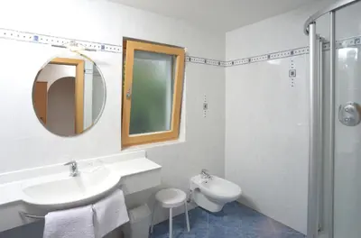 a white bathroom with a sink and a mirror at Kampflhof Apartments in Schenna