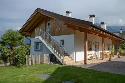 a house with a wooden roof and a patio at Kampflhof Apartments in Schenna