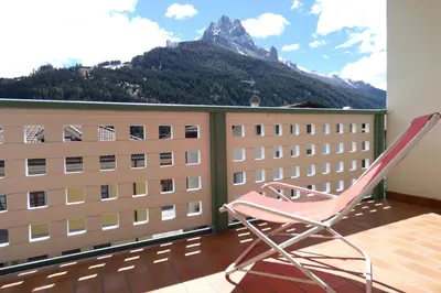 a chair on a balcony with a view of a mountain at Casa Al Mesdì in Pozza di Fassa