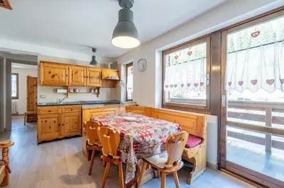 a kitchen with a table and chairs and windows at Cesa de Paio in Mazzin