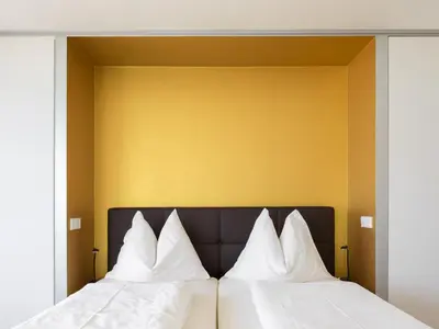 two beds with white pillows in front of a yellow wall at Villa Alvarium in Schenna