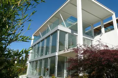 a large white building with glass windows at Villa Alvarium in Schenna
