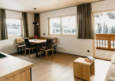 a living room with a table and chairs and windows at Apartments Broslhof in Racines