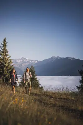 two people walking on a hill with a view of a lake at Apartments Broslhof in Racines