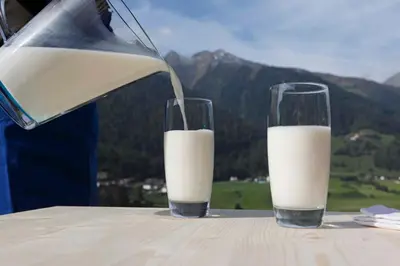a person pouring milk into two glasses on a table at Apartments Broslhof in Racines