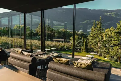 a living room with couches and a large glass window at Design Hotel Tyrol in Rablà