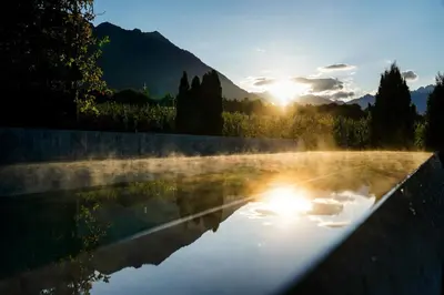 a pool of water with the sun in the background at Design Hotel Tyrol in Rablà