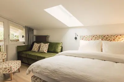a bedroom with a bed and a green couch at Pomella's Guesthouse in Cortaccia