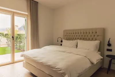 a bedroom with a large bed and a large window at Pomella's Guesthouse in Cortaccia