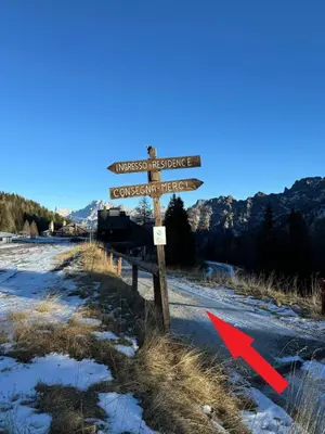 a street sign with a red arrow next to a road at Casa Serenity in Falcade