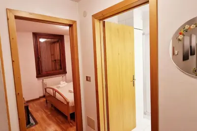 a room with a hallway with a mirror and a bathroom at trilocale panorama val di fiemme in Predazzo