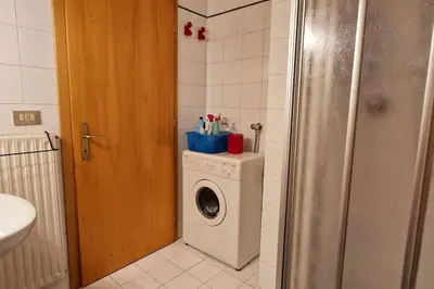 a bathroom with a washing machine and a washer at trilocale panorama val di fiemme in Predazzo