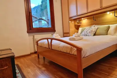a bedroom with a large bed with a window at trilocale panorama val di fiemme in Predazzo