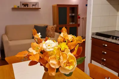 a vase filled with yellow and white flowers on a table at trilocale panorama val di fiemme in Predazzo