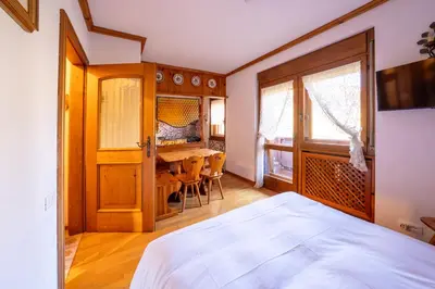 a bedroom with a bed and a table with chairs at GuestHost - Silent Peaks - Cortina's Wooden Haven in Cortina dʼAmpezzo