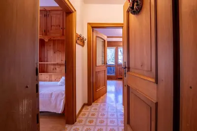 a hallway leading to a bedroom with a bed at GuestHost - Silent Peaks - Cortina's Wooden Haven in Cortina dʼAmpezzo