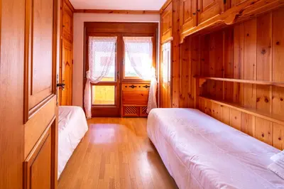 a bedroom with two beds and a window at GuestHost - Silent Peaks - Cortina's Wooden Haven in Cortina dʼAmpezzo