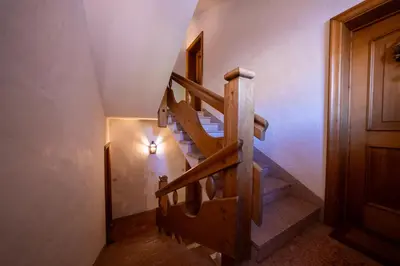 a wooden staircase in a house with a light on the wall at GuestHost - Silent Peaks - Cortina's Wooden Haven in Cortina dʼAmpezzo