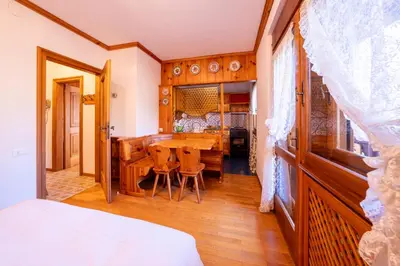 a bedroom with a table and chairs and a dining room at GuestHost - Silent Peaks - Cortina's Wooden Haven in Cortina dʼAmpezzo