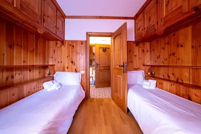 two beds in a room with wooden walls at GuestHost - Silent Peaks - Cortina's Wooden Haven in Cortina dʼAmpezzo