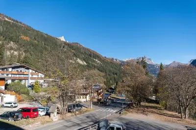 a town with cars parked in a parking lot next to a mountain at Appartamento Lucia 203 in Vigo di Fassa