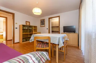 a living room with a table and chairs and a television at Appartamento Alessandra 106 in Vigo di Fassa