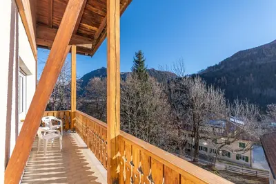 a wooden balcony with a table and a chair on it at Appartamento Alessandra 204 in Vigo di Fassa