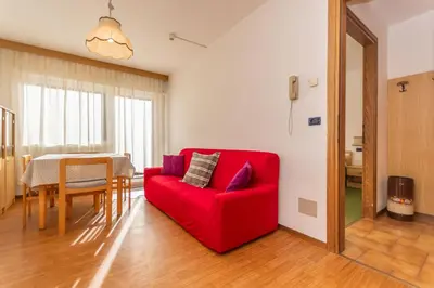 a red couch in a living room with a table at Appartamento Alessandra 204 in Vigo di Fassa