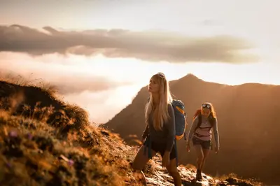 two women walking up a hill on a mountain at Stadtnestl Apartment in Vipiteno