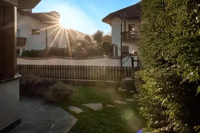 a fence in front of a house with the sun at Stadtnestl Apartment in Vipiteno