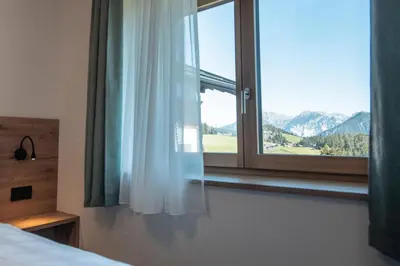 a bedroom with a window with a mountain view at Ciasa Sabine in Antermoia