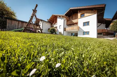 a house on a grassy hill with a windmill at Ciasa Sabine in Antermoia