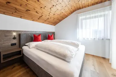 a bedroom with a large white bed with red pillows at Ciasa Sabine in Antermoia