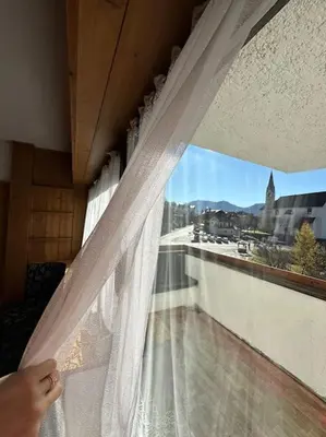 a person is looking out of a window at a view at Appartamento da Zambon in San Vito di Cadore