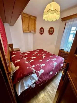 a bedroom with a bed with red sheets and a chandelier at Appartamento da Zambon in San Vito di Cadore