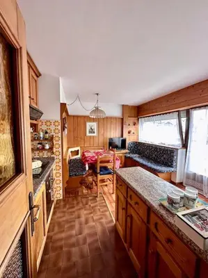 a kitchen with a counter and a living room at Appartamento da Zambon in San Vito di Cadore