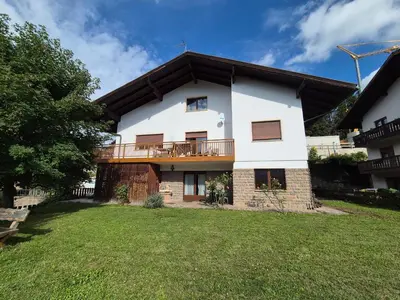 a large white house with a balcony and a yard at La casa sul giardino in Castello di Fiemme