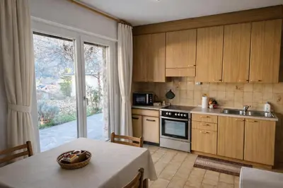 a kitchen with wooden cabinets and a table with a table cloth at La casa sul giardino in Castello di Fiemme