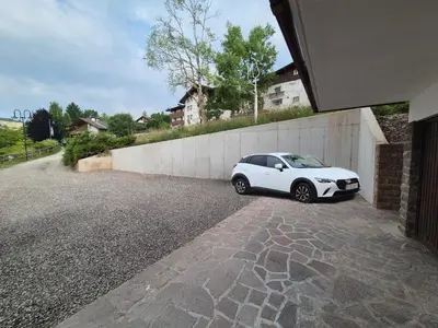 a white car parked next to a wall at La casa sul giardino in Castello di Fiemme