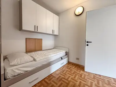 a small room with a bed and white cabinets at Chalet Vernel in Canazei