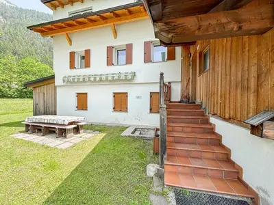 a house with a table and a bench in the yard at Chalet Vernel in Canazei