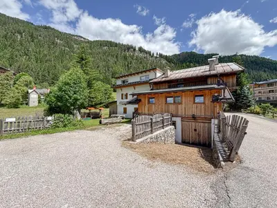 a large wooden house with a fence and a driveway at Chalet Vernel in Canazei