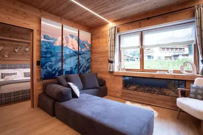 a living room with a couch and a large window at Appartamento Le Due Cime a Pozza di Fassa TRENTO in Pozza di Fassa