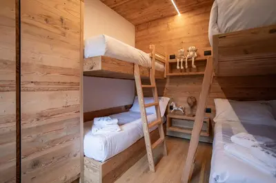 a room with two bunk beds in a cabin at Appartamento Le Due Cime a Pozza di Fassa TRENTO in Pozza di Fassa
