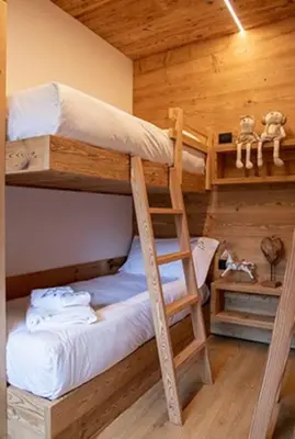 two bunk beds in a room with a ladder at Appartamento Le Due Cime a Pozza di Fassa TRENTO in Pozza di Fassa