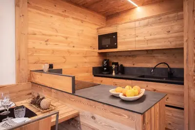 a kitchen with wooden walls and a counter with a bowl of fruit at Appartamento Le Due Cime a Pozza di Fassa TRENTO in Pozza di Fassa