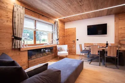 a living room with a fireplace and a dining room at Appartamento Le Due Cime a Pozza di Fassa TRENTO in Pozza di Fassa