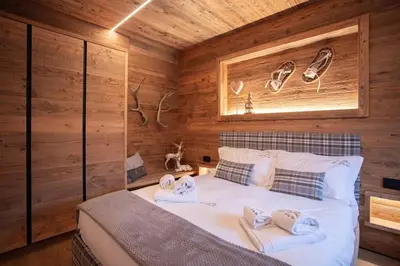 a bedroom with a bed in a log cabin at Appartamento Le Due Cime a Pozza di Fassa TRENTO in Pozza di Fassa